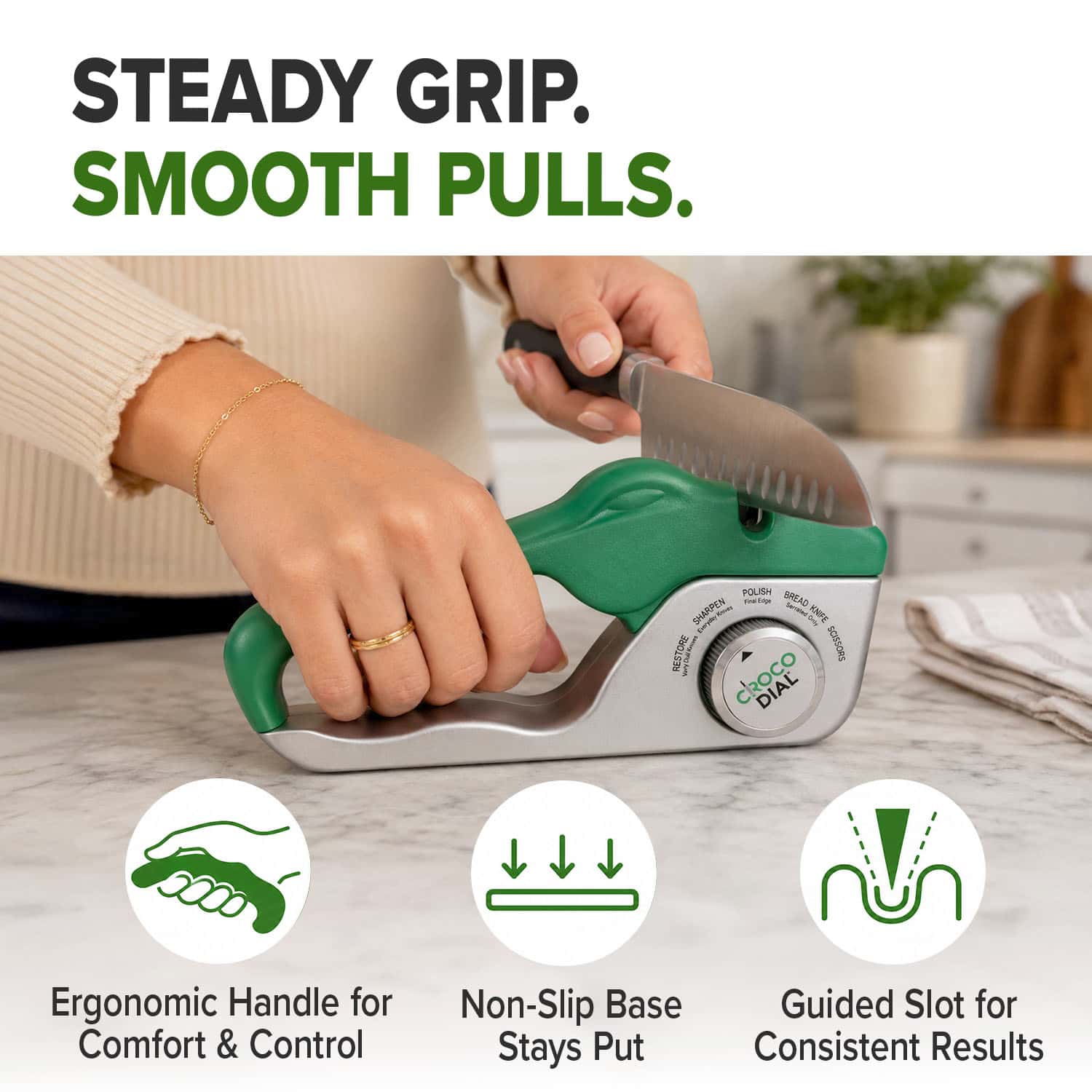 A person sharpens a knife on a kitchen counter with the green and silver Croco Dial 5-in-1 sharpening system, featuring an ergonomic handle, non-slip base, and guided slot for consistent results.