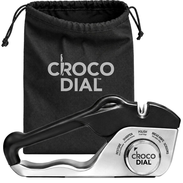 The Croco Dial multi-stage knife sharpener with a black handle and silver base, positioned in front of a black drawstring storage bag as part of a sharpening system.