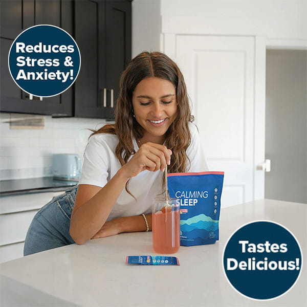 A woman in a kitchen stirs a pink drink beside a Calming Sleep (Includes 30 Packs) packet featuring ashwagandha and magnesium glycinate, with text on the image: Reduces Stress & Anxiety! and Tastes Delicious!.