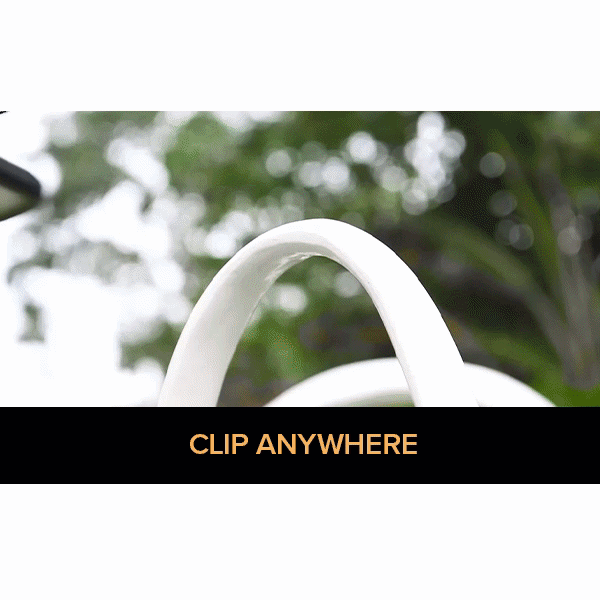 A hand clips a Clip On Outdoor Solar Light (Pack of 2) onto items like a purse, stroller, and shopping cart—showing its versatility. Text reads "CLIP ANYWHERE." Outdoor greenery forms the backdrop.