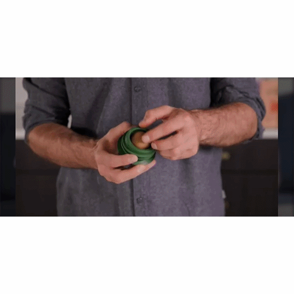 A person in a gray shirt holds a Dog Treat Toy With Refill Treats, unscrews the green yo-yo-shaped toy, and reveals a hidden compartment inside—ideal for stashing Peanut Butter Dog Treats or other Long Lasting Dog Chews for an innovative dog enrichment experience.