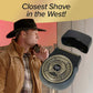 A man in a cowboy hat holds the Shave Sheriff, a round waterproof cordless shaver with a sheriff badge design. The text reads “Closest Shave in the West!” and the digital display on the shaver shows “100.”.