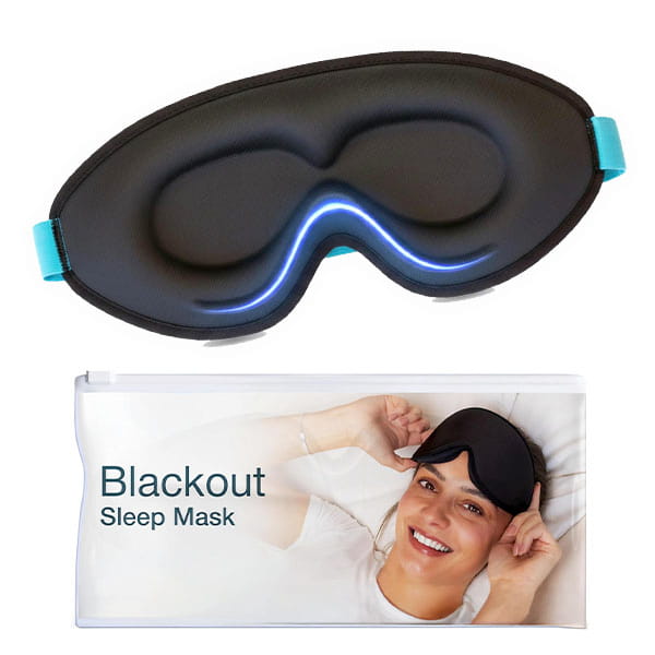 A Blackout Sleep Mask in black with teal straps is displayed above its packaging, which shows a smiling person in bed wearing the mask. The package highlights the Blackout Sleep Mask’s light-blocking design for a restful night.