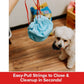 A hand pulls the easy-close strings on the blue Drawstring Pee Pad (Includes 25 Pads) bag while a small white dog looks on. Text below reads: Easy-Pull Strings to Close & Cleanup in Seconds!.