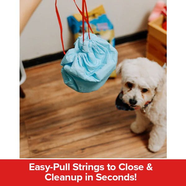 A hand pulls the easy-close strings on the blue Drawstring Pee Pad (Includes 25 Pads) bag while a small white dog looks on. Text below reads: Easy-Pull Strings to Close & Cleanup in Seconds!.