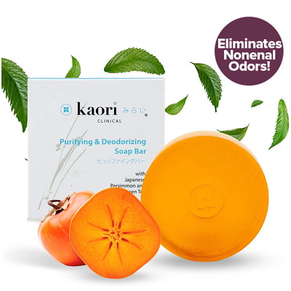 A Kaori Soap Bar for Old People Smell round soap bar next to a halved Japanese persimmon and its product box, with a circular badge stating it eliminates nonenal odors and floating green leaves.