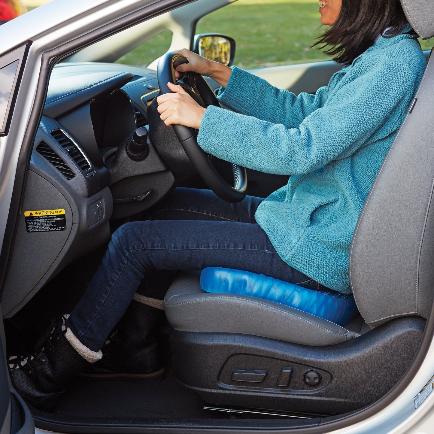 Woman sitting on Egg Sitter Support Cushion in driver's seat of a car