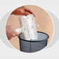 Close up of woman's hands holding a Pet Hair Remover over a trashcan with the pet hair compartment open and dumping the hair out