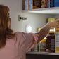 Woman reaching into pantry and an Atomic Beam TapLight is lit up on the wall inside